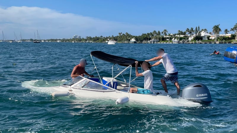A U.S. Coast Guard Station Lake Worth Inlet rescue crew assists three crewmembers aboard a...