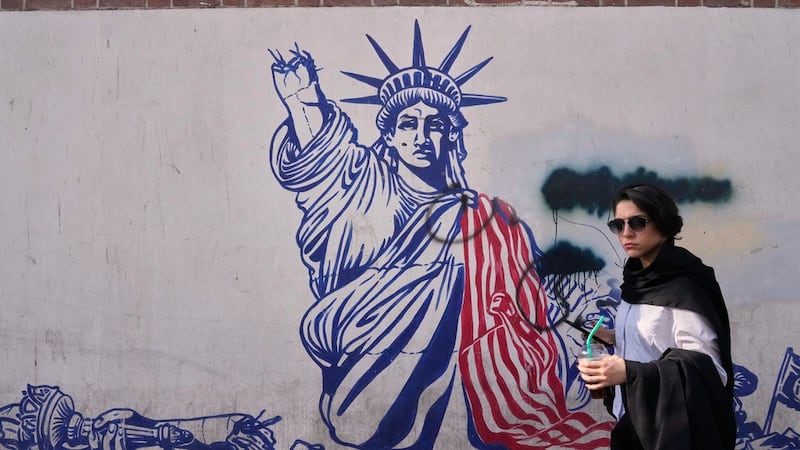 Una mujer pasa junto a un mural antiestadounidense en la pared de la antigua embajada de...